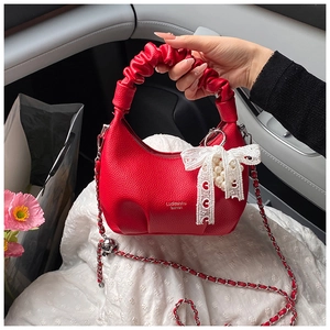 Detail of red crescent bag with lychee texture leather and lace pearl bow charm