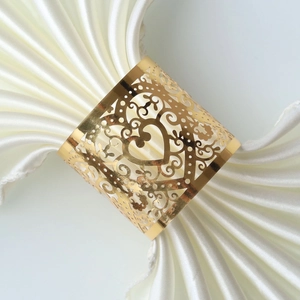 Macro shot of gold heart napkin ring with floral cutouts on white silk fabric