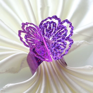 Close-up of laser-cut purple butterfly napkin ring with glitter finish on cream fabric