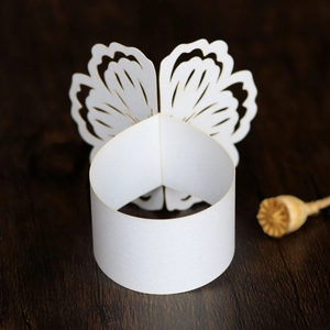 Close-up of white laser-cut butterfly paper napkin ring on dark wood surface