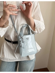 Minimalist light blue patent leather crossbody phone bag with heart pendant detail