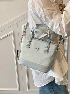 Elegant light blue faux leather bucket bag with silver logo and adjustable strap