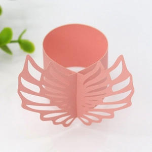 Detail of pink pearlescent paper napkin ring with laser-cut hollow angel wing design