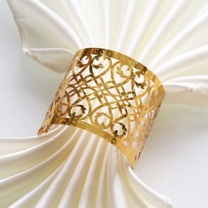 Detail of gold glitter hollow napkin ring with elegant floral filigree on white satin
