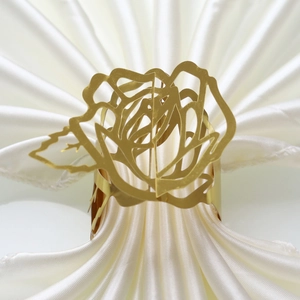 Detailed view of elegant golden rose napkin ring on white satin fabric for wedding table decor