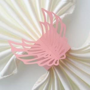 Detail of pink pearl paper napkin ring with laser-cut angel wing design for weddings