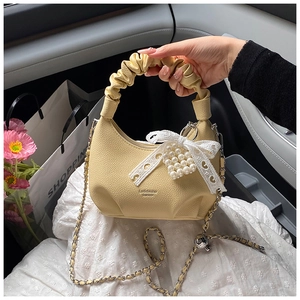 Detailed macro view of yellow lychee leather handbag with lace bow and pearl cluster