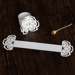 Laser-cut white paper napkin ring with elegant floral pattern for wedding table decor