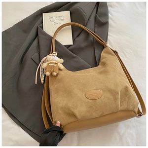Detail of khaki tote bag with suede texture and a cute decorative bear charm pendant