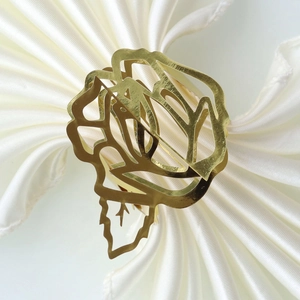 Close-up of golden hollow rose napkin ring on a white satin cloth for table setting