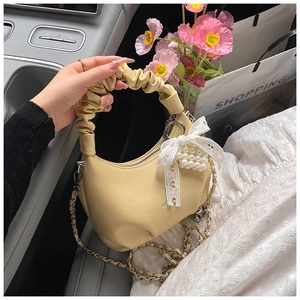 Detail of yellow cloud bag with lace bow, pearl heart charm and metal chain strap
