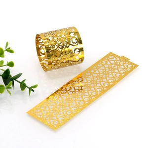 Detail view of laser-cut gold glitter napkin rings with elegant vine pattern design