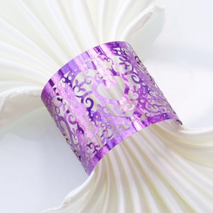 Macro shot of purple laser-cut heart napkin ring with floral scrollwork on silk