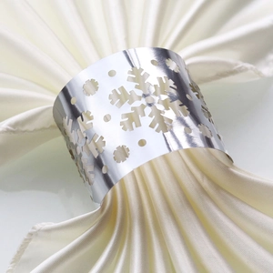 Close-up of a silver snowflake napkin ring on a beige satin napkin for festive tables