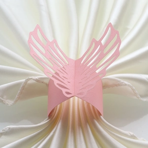 Detailed close-up of pink laser-cut butterfly wing paper napkin ring on silk cloth