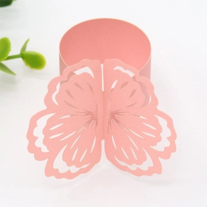 Detailed view of pink laser-cut paper napkin ring with elegant floral hollow pattern