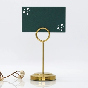 Close-up of golden heart place card holder with a dark green hollowed heart card