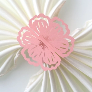 Close-up of pink pearlescent paper flower napkin rings with laser-cut hollow details