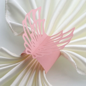 Pink pearlescent paper napkin rings featuring laser-cut angel wing design for weddings