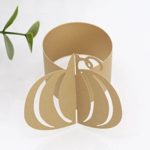 Detailed macro view of laser-cut gold pumpkin paper napkin ring for Halloween table decor