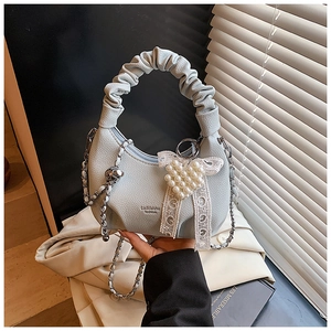 Detail of light blue crescent bag with pearl heart charm and lace bow decoration