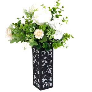 Detail of elegant black openwork floral vase with white roses and yellow pompons