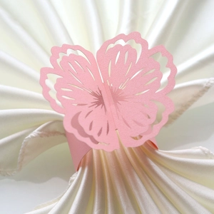 Laser-cut pearlescent pink paper butterfly napkin ring with elegant hollow floral pattern