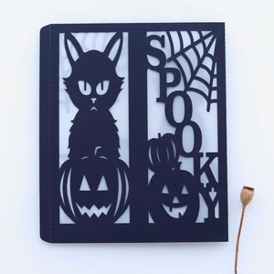 Detail of laser-cut Halloween spooky card featuring a black cat, pumpkin, and spider web