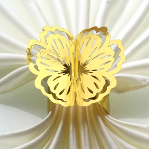 Macro detail of golden butterfly napkin ring with intricate laser-cut hollow design