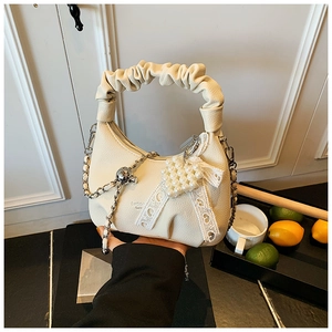 Detail of beige crescent bag with lychee texture, pearl heart charm and lace bow