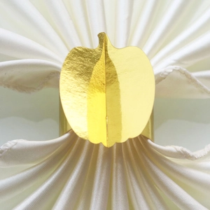 Macro shot of mirror-finish gold pumpkin napkin ring on elegant white silk cloth