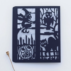 Detail of laser-cut Halloween paper lantern featuring witch, pumpkin and owl motifs