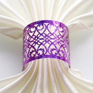 Close-up of glitter purple hollow heart-shaped napkin ring on white satin fabric
