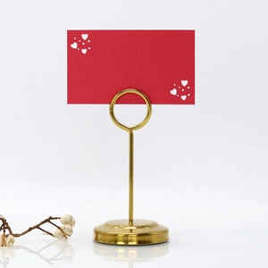 Close-up of golden heart table card holder with thick round base and red name card