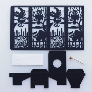 Flat lay of laser-cut Halloween paper lantern kit with witch and pumpkin patterns