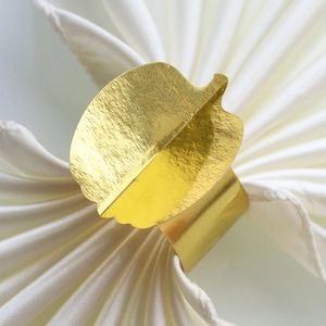 Macro detail of golden pumpkin napkin ring with brushed metal texture for Thanksgiving