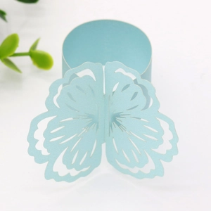 Detail of light blue laser-cut butterfly paper napkin ring with intricate hollow patterns