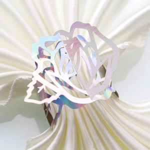 Macro detail of laser-cut rose napkin ring with iridescent holographic finish on fabric