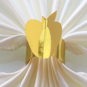Detailed view of 3D golden apple napkin ring on white satin fabric for Thanksgiving