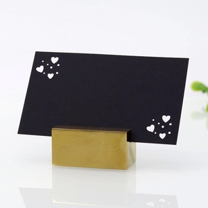 Close-up of golden metal card holder with elegant heart-shaped hollow black table card