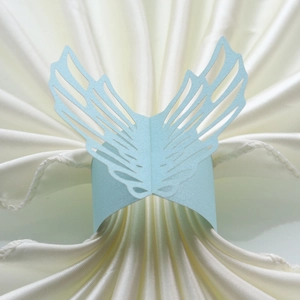 Macro detail of laser-cut light blue pearlescent paper napkin ring with wing design