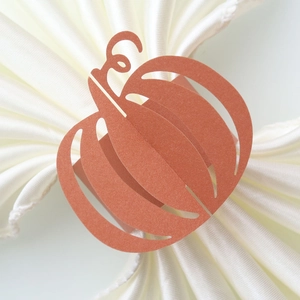 Detail of orange paper pumpkin napkin ring with laser-cut hollow design for Halloween