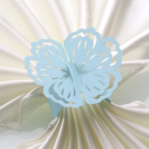 Macro detail of laser-cut light blue paper butterfly napkin ring with hollow floral pattern