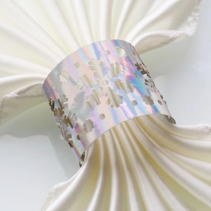 Macro view of holographic laser-cut snowflake napkin ring on white satin fabric