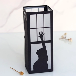 Detail of laser-cut witch silhouette on a black rectangular paper lantern for Halloween