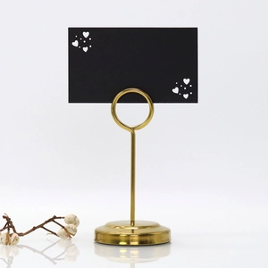 Detail of gold metal table card holder with round base and minimalist heart clip stand