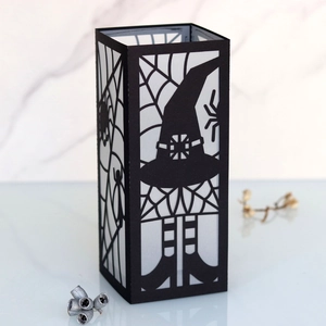 Detail of laser-cut Halloween spider web and witch hat patterns on a black paper lantern