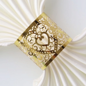 Detail of laser-cut golden heart napkin ring with intricate scrollwork on white fabric