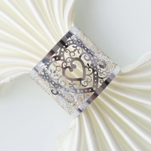 Detail of silver heart-shaped napkin ring with laser-cut floral patterns on satin