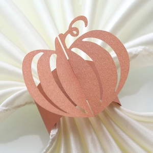 Close-up of rose gold pumpkin napkin ring with glitter finish on white fabric